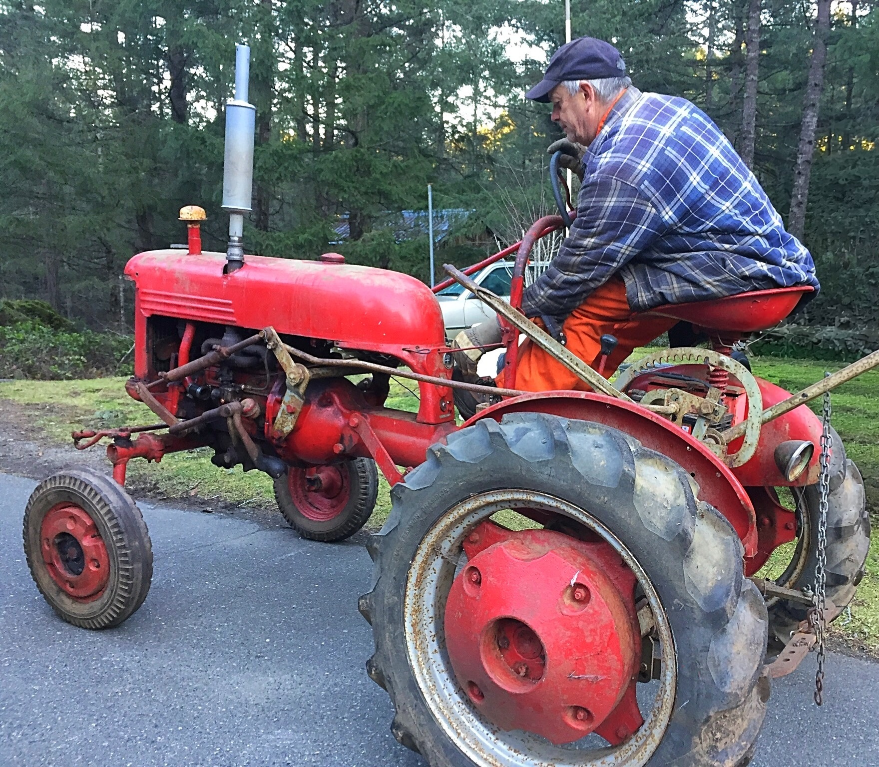 Rob driving a red tractor in a wooded setting
